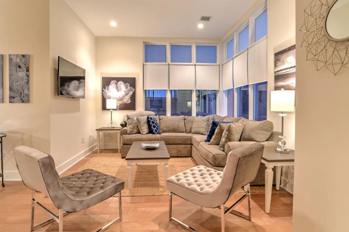 This image features a modern living room with a sleek sofa, a stylish coffee table, and eye-catching decorative artwork. Large windows allow natural light to flood the space, creating a bright and inviting atmosphere perfect for relaxation or social gatherings.