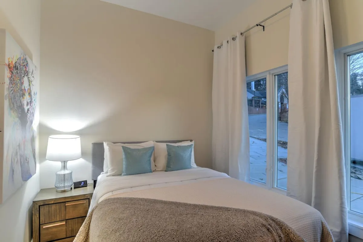 A cozy bedroom scene featuring a plush bed with premium linens, a soft lamp, and serene artwork. The mood is restful and inviting, emphasizing comfort and relaxation after a busy day downtown.