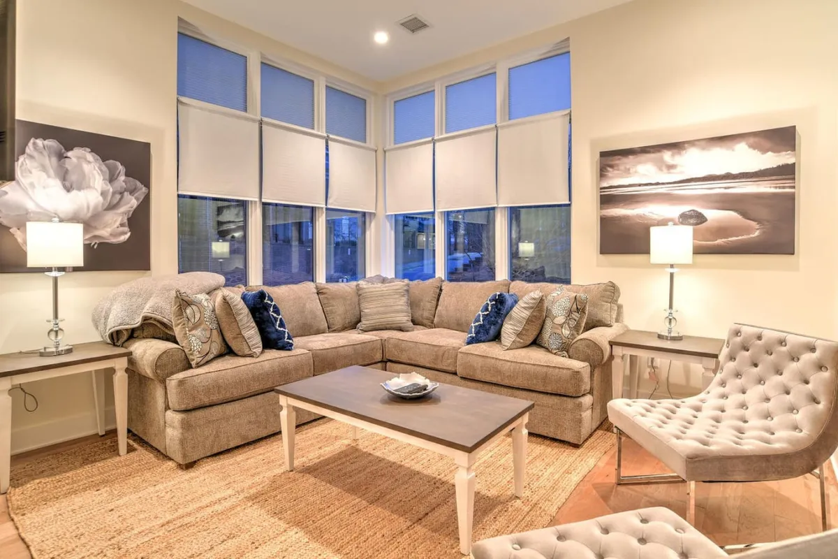 The image showcases a stylish and inviting living room with a plush sofa, a modern coffee table, warm lighting from elegant lamps, and vibrant artwork adorning the walls. The atmosphere feels cozy and perfect for relaxing, socializing, or enjoying a quiet evening in.